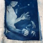 Cyanotype on fabric of a woman labeling bananas with stickers & Banana Land (front page)
